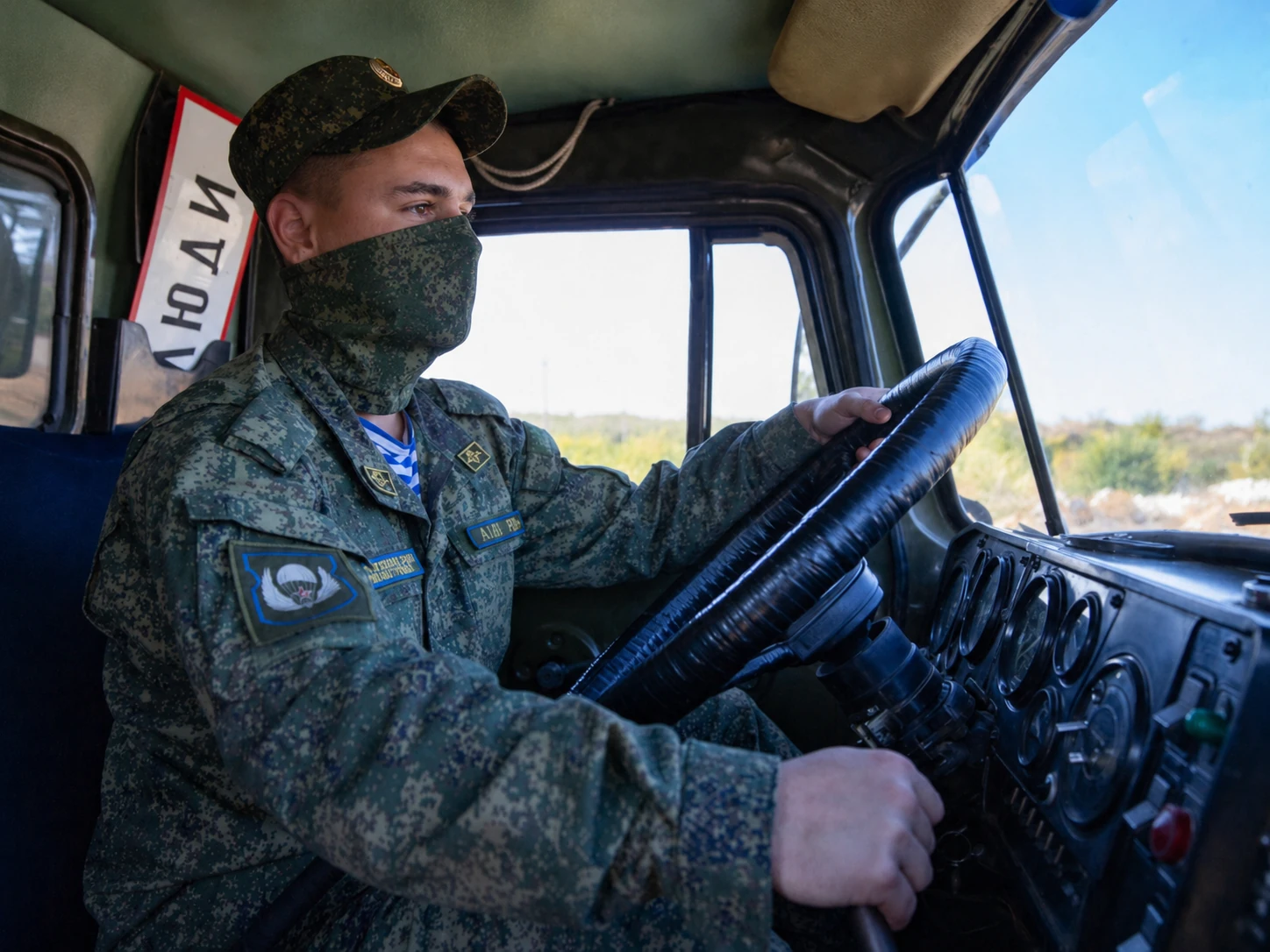 Водитель военного грузовика за рулём